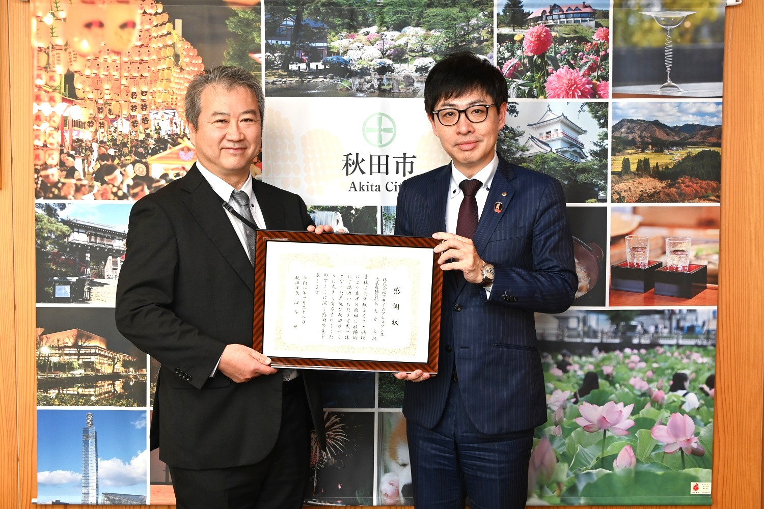 大倉社長と沼谷秋田市長が笑顔で感謝状を持っている様子